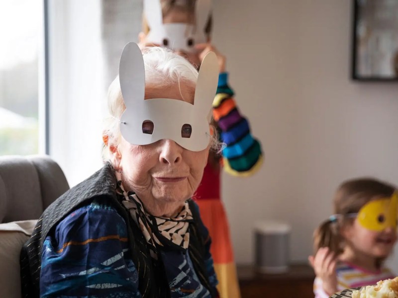 Großmutter und Enkelkinder tragen Hasenmasken.