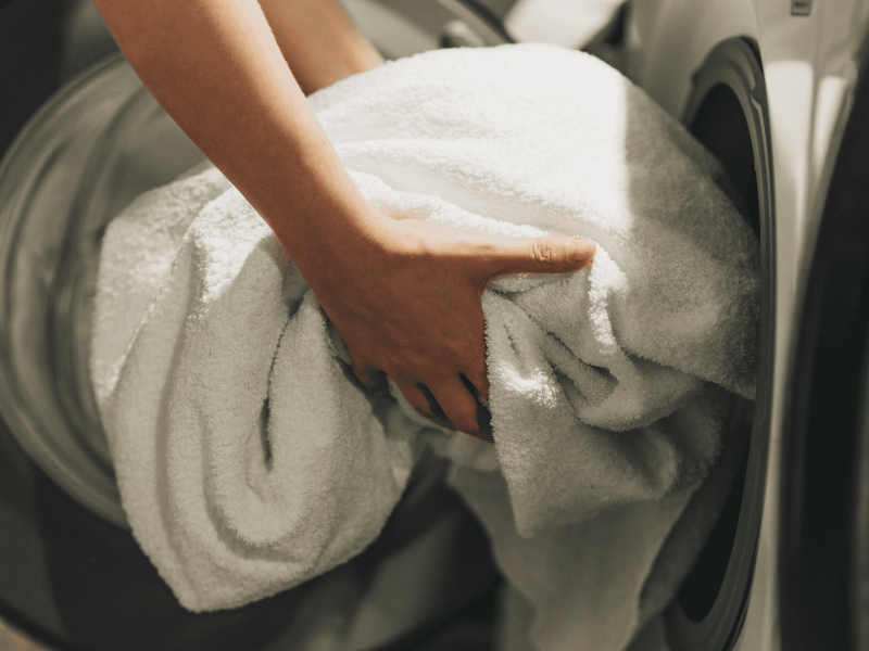 Person holt Wäsche aus dem Trockner