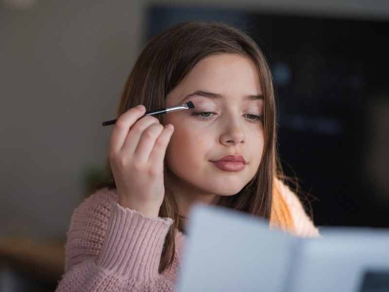 Junges Mädchen, das Lidschatten aufträgt.