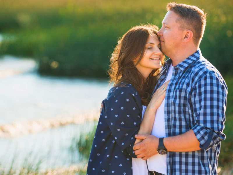 Paar am Strand. Frau schmiegt sich an ihren Partner.