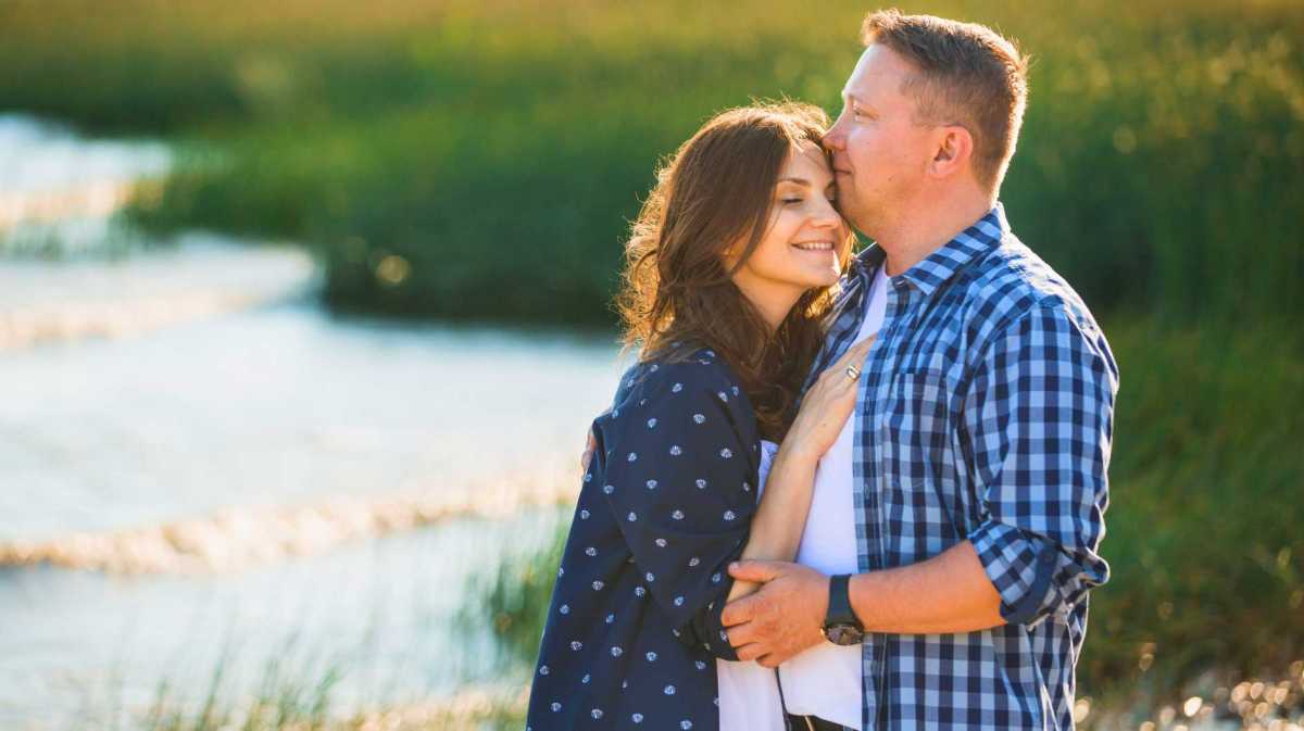 Paar am Strand. Frau schmiegt sich an ihren Partner.