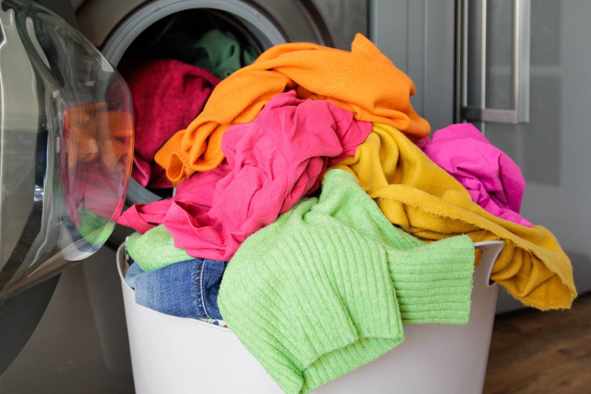 Wäschekorb mit Buntwäsche vor Waschmaschine