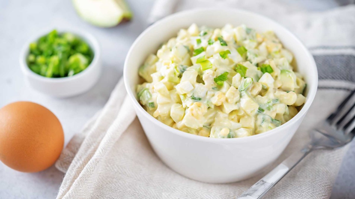 Eine Schüssel mit Eiersalat steht auf einem Tisch mit Tischdecke.