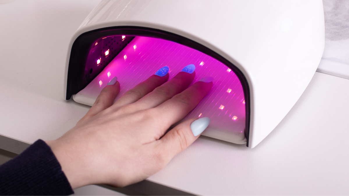 Hand mit blauem Gellack in UV Lampe