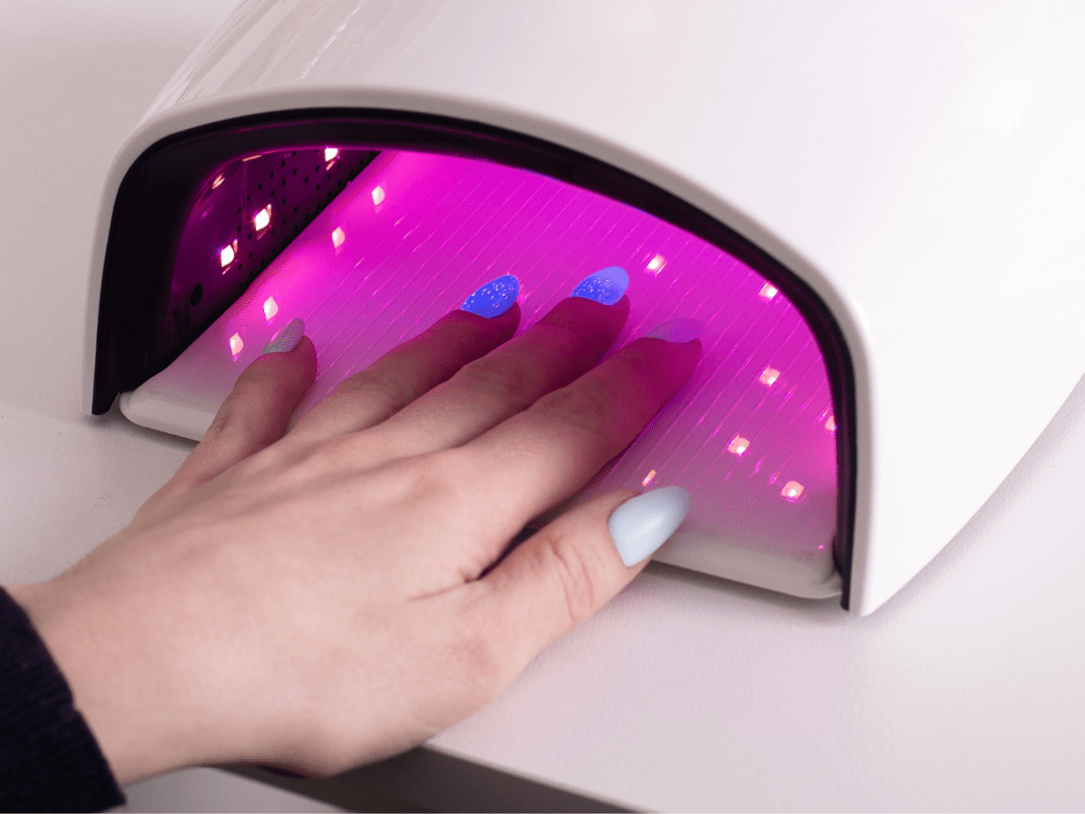 Hand mit blauem Gellack in UV Lampe