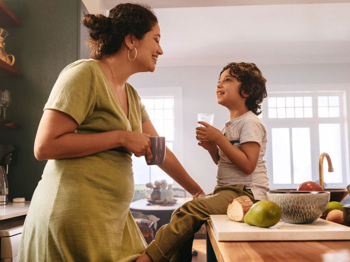 Gl&uuml;ckliche Mutter und ihr Sohn in der K&uuml;che lachen sich an.