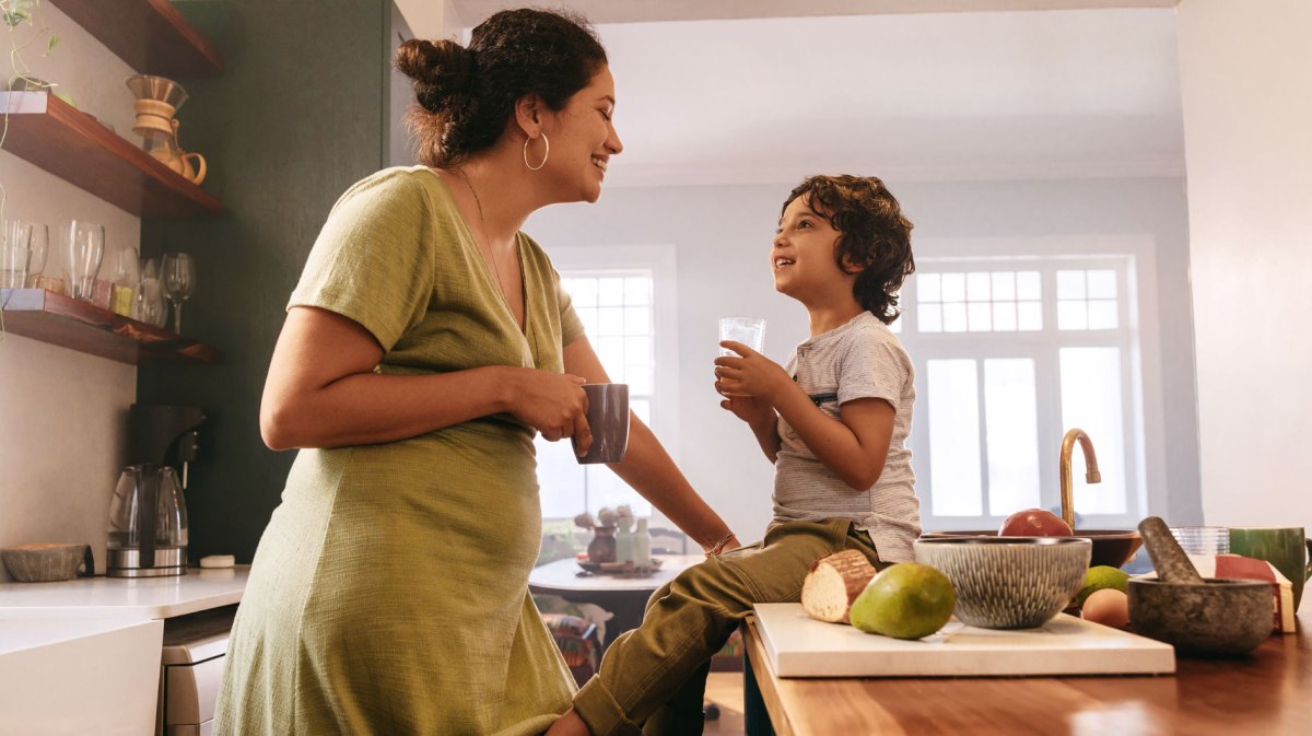 Glückliche Mutter und ihr Sohn in der Küche lachen sich an.