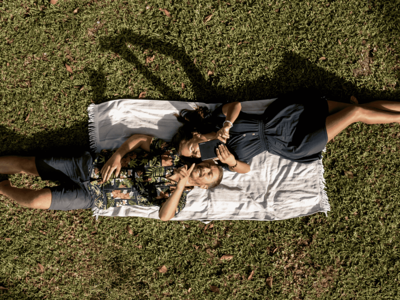 Mann und Frau liegen auf Wiese und legen mit einem PocketBook eReader.