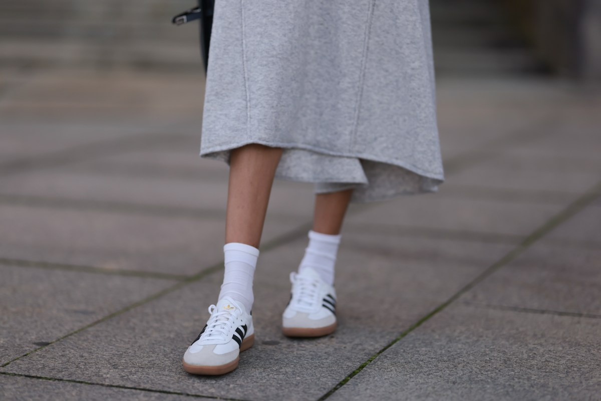 Nahaufnahme graues Wollstrickkleid, weiße Baumwollsocken und weiße Adidas-Leder-Samba-Sneaker.