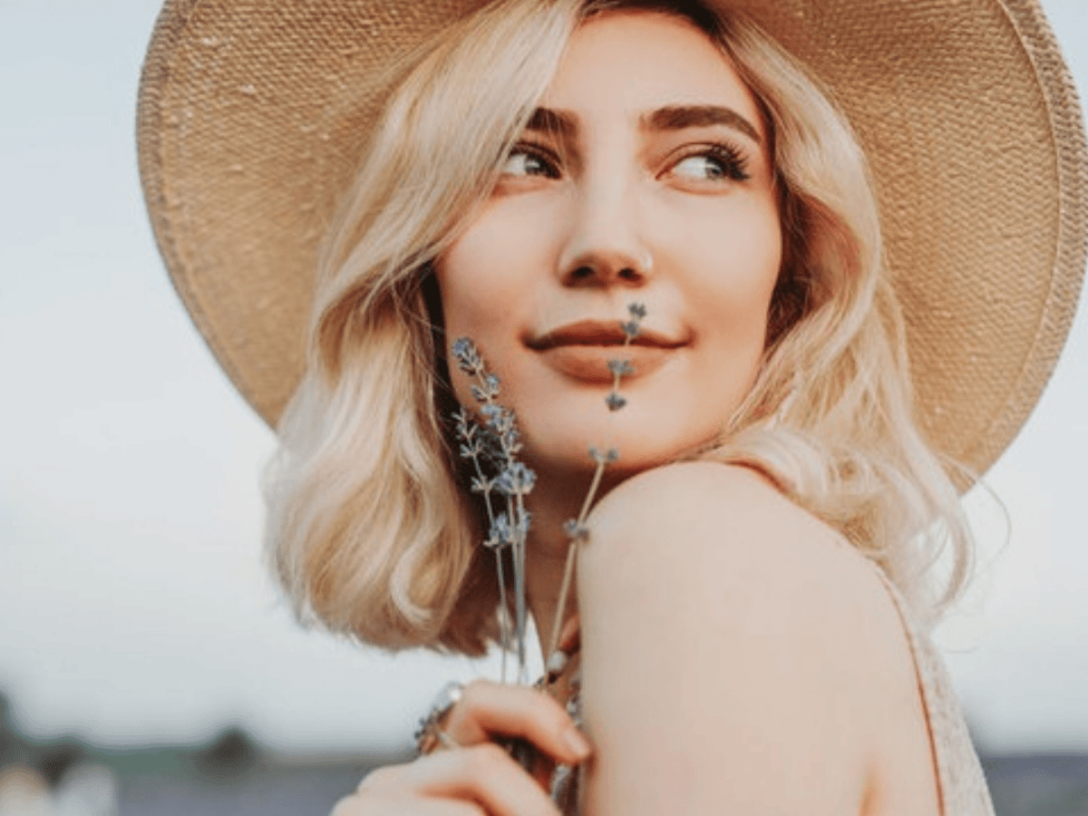Junge Frau mit blonden Haaren h&auml;lt Lavendel vor ihr Gesicht.