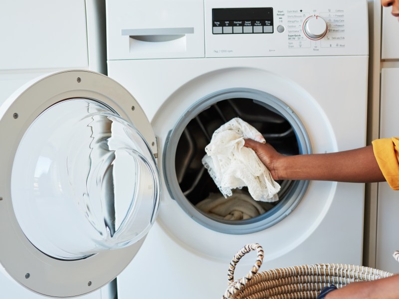 Frau legt weiße Wäsche in die Waschmaschine