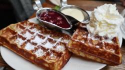 Belgische Waffeln mit Kirschen und Sahne und Puderzucker.