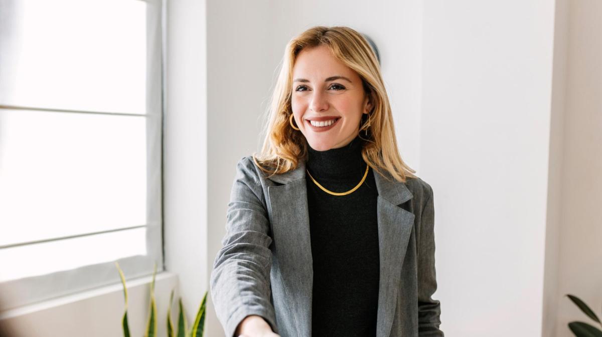 Junge blonde Frau mit grauem Blazer.