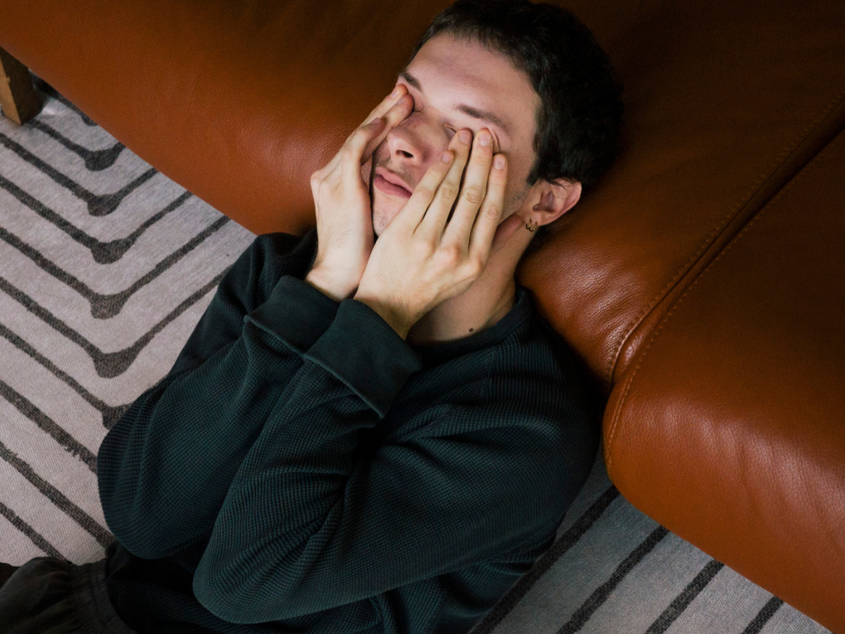 Junger Mann h&auml;lt sich die H&auml;nde vor das Gesicht