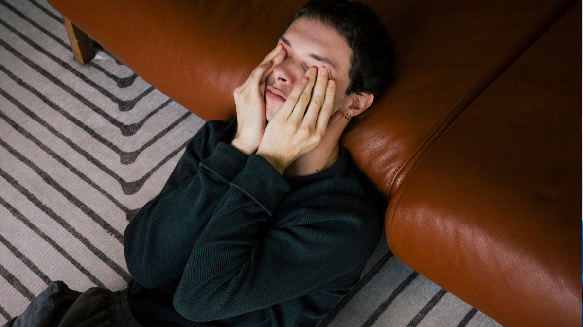 Junger Mann hält sich die Hände vor das Gesicht