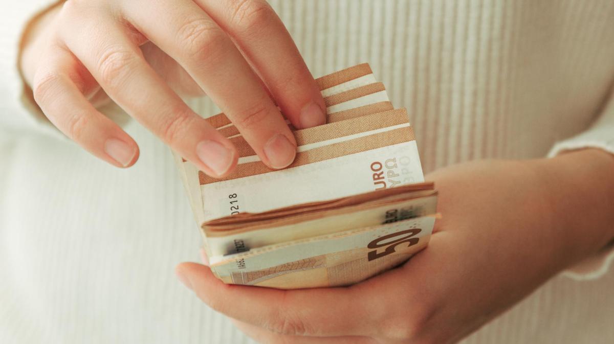 Frau mit hellem Pulli zählt 50-Euro-Scheine.