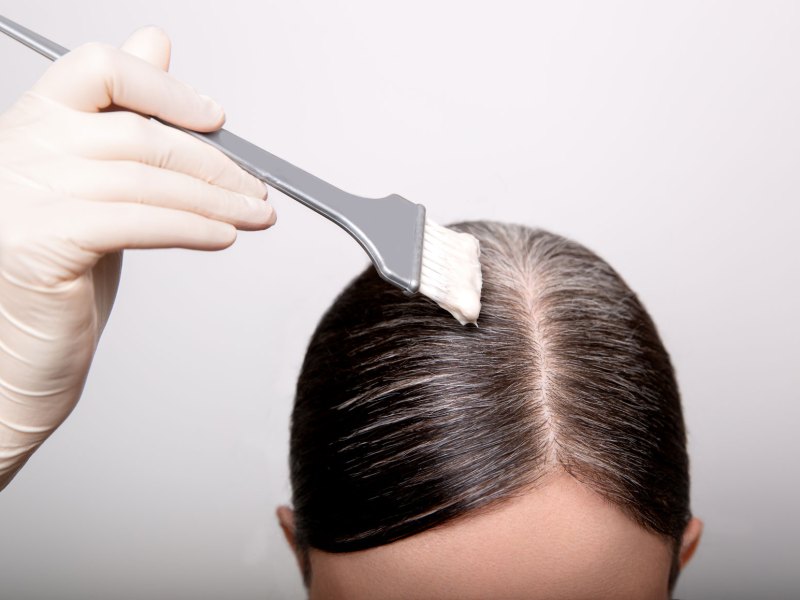 Frau, die gerade ihre graun Ansätze färbt.