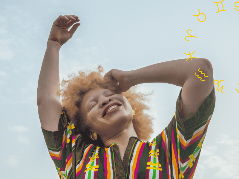 Frau streckt lächelnd ihre Arme in den Himmel