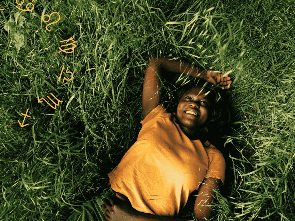 Frau mit gelbem Shirt liegt lächelnd im Rasen