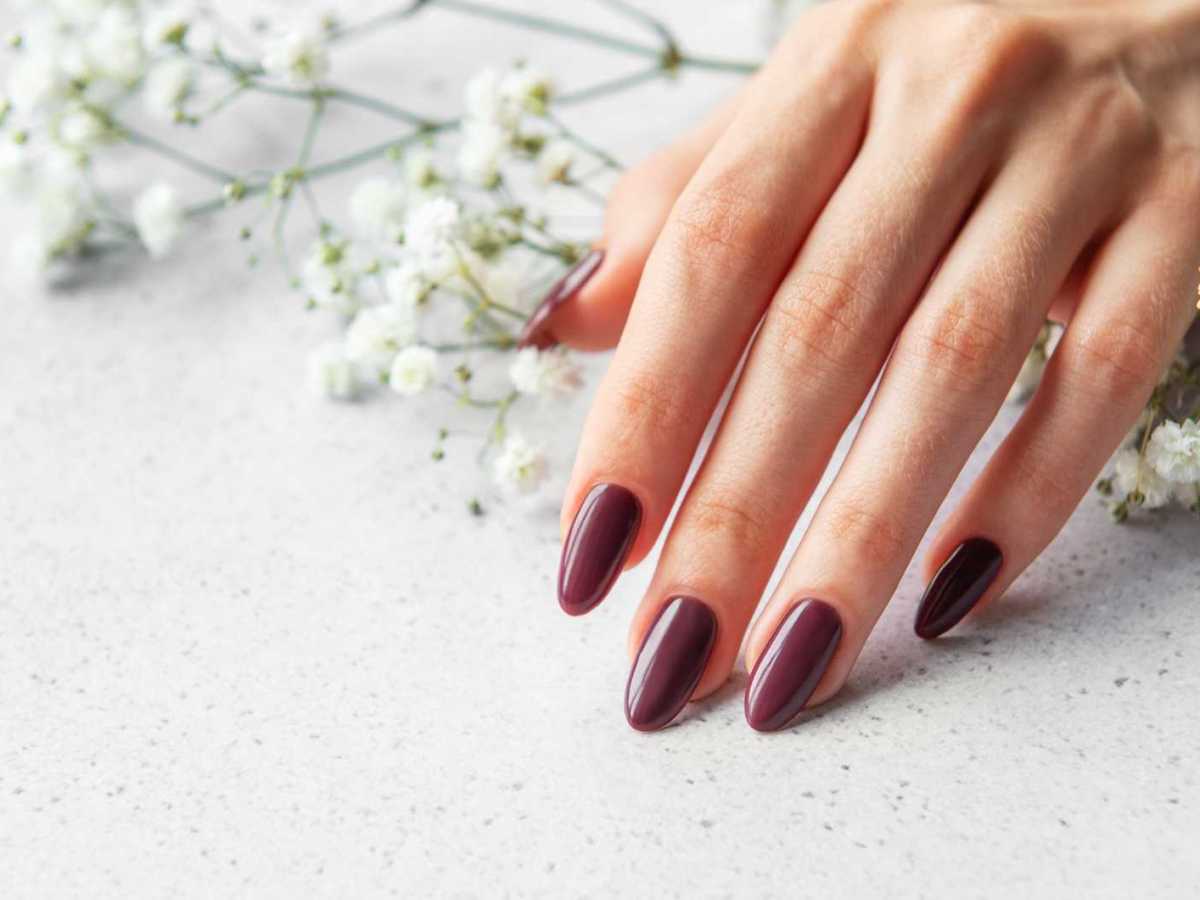 Rot lackierte Fingern&auml;gel vor wei&szlig;en Blumen