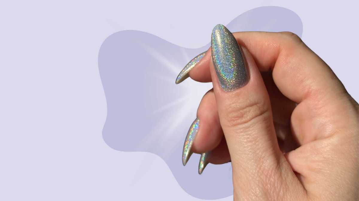 Holografische Nägel in einem grauen Farbton vor einem lilafarbenen Hintergrund