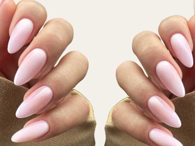 Mandelförmige rosa Nägel vor einem beigen Hintergrund