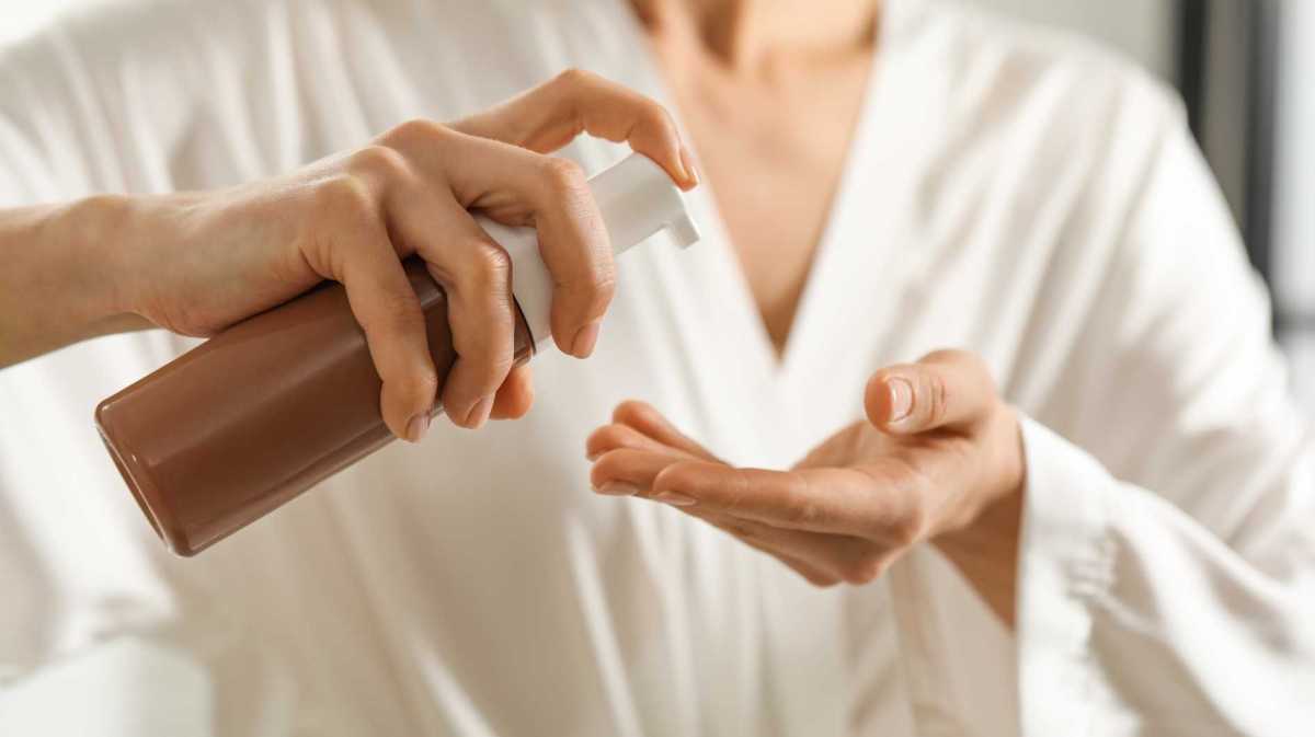 Frau gibt Selbstbräuner in die Handflächen