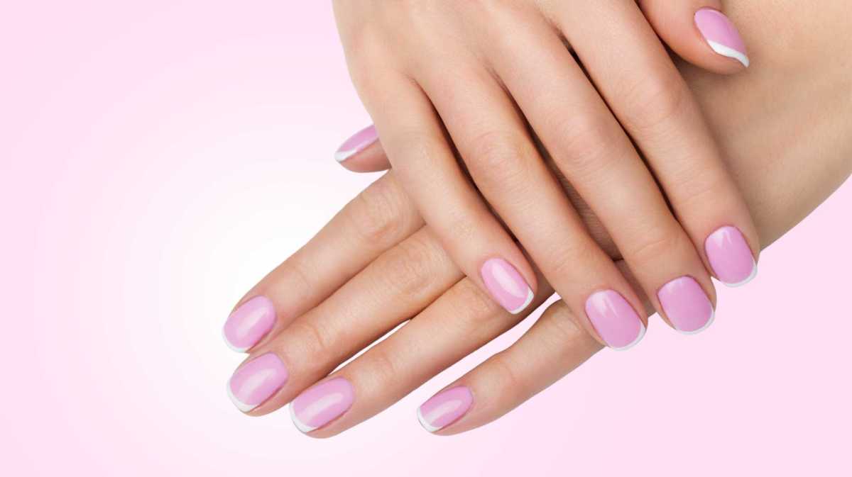 Nägel mit French Design vor einem rosa Hintergrund