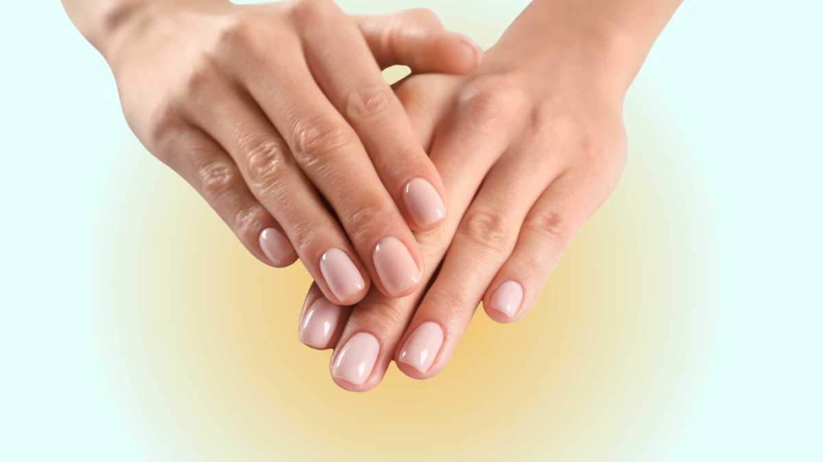 Zwei Hände mit rosa lackierten Fingernägeln werden vor einen blau-orangenen Hintergrund gehalten