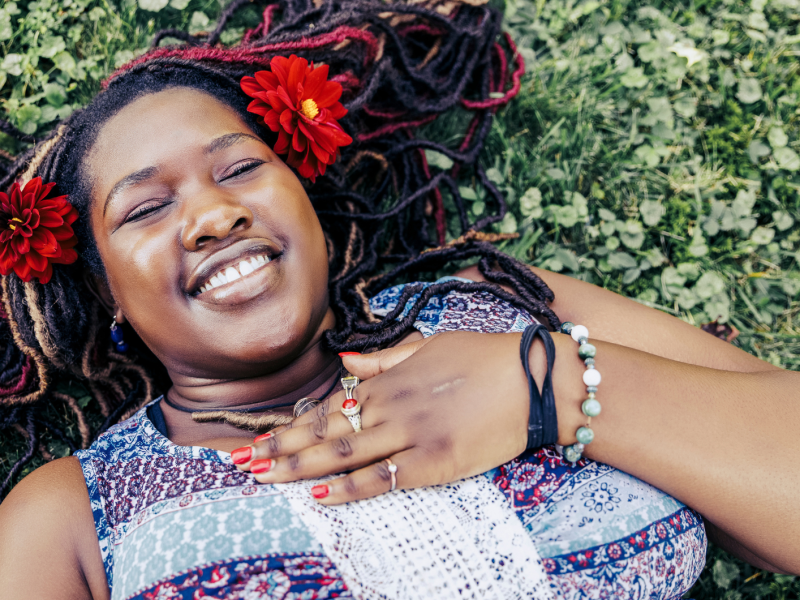 Lächelnde Frau mit Blumen im Gras.