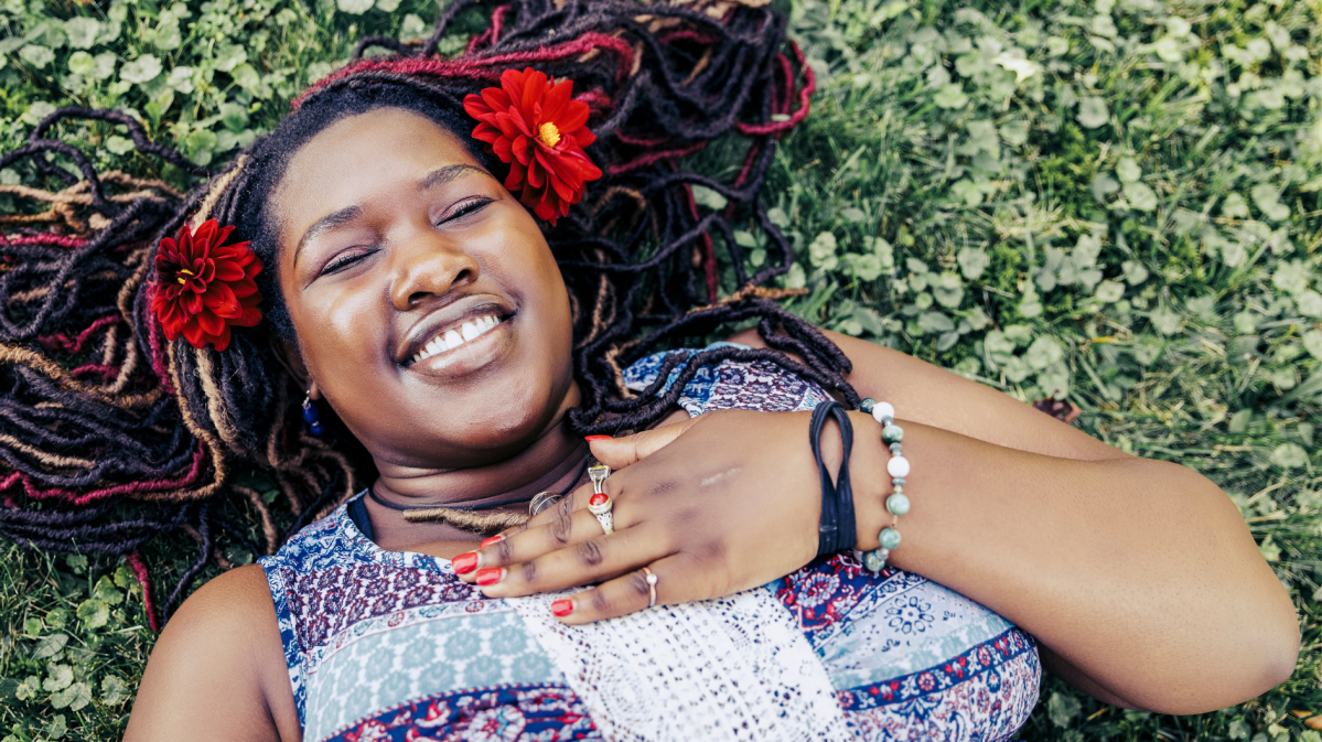 Lächelnde Frau mit Blumen im Gras.