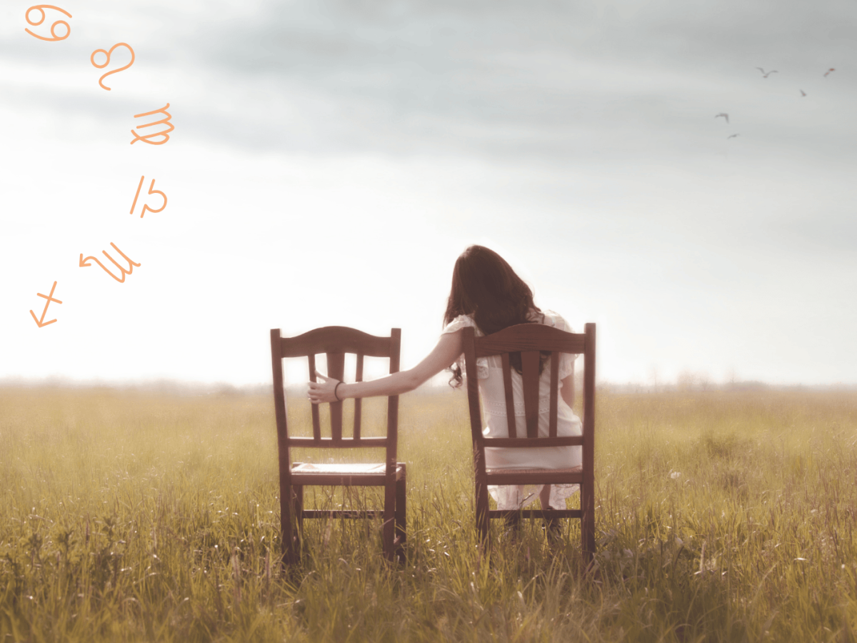 Frau sitzt auf dem Feld auf einem Stuhl und h&auml;lt Hand auf leeren Stuhl neben ihr