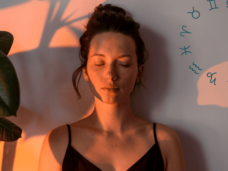 Frau mit geschlossenen Augen an Wand gelehnt wird von Sonnenuntergangslicht angeleuchtet