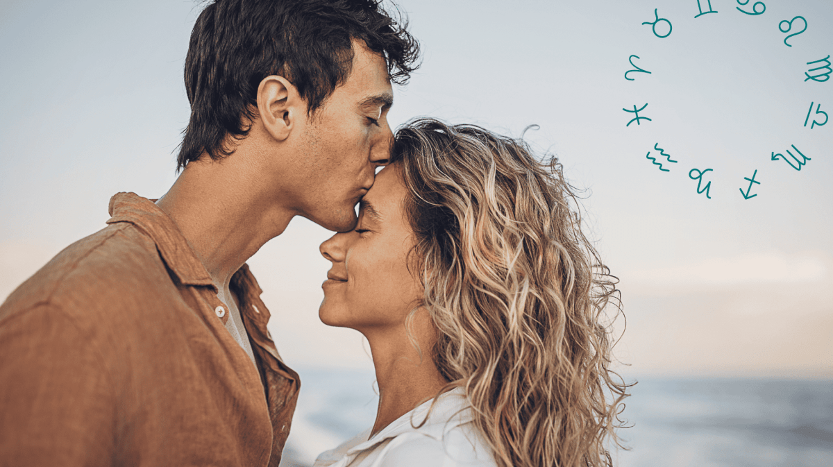 Mann küsst Frau am Strand auf die Stirn
