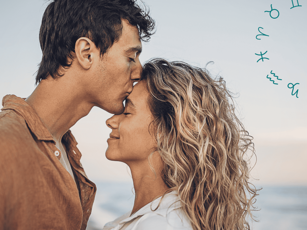 Mann küsst Frau am Strand auf die Stirn