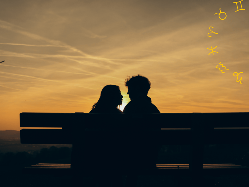 Frau und Mann sitzen bei Sonnenuntergang auf einer Bank und schauen sich an.