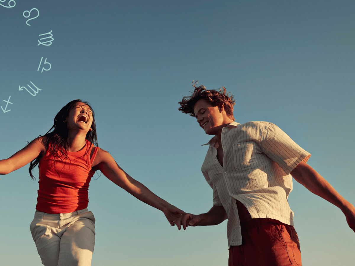 Frau und Mann halten sich an der Hand und lachen zusammen vor blauem Himmel