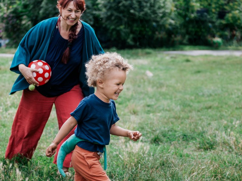 Enkel spielt mit seiner Oma im Park Fangen.