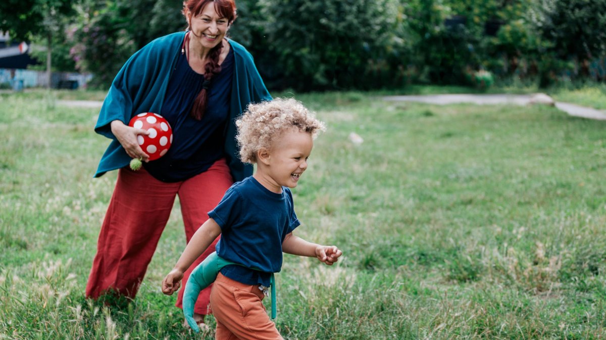 Enkel spielt mit seiner Oma im Park Fangen.