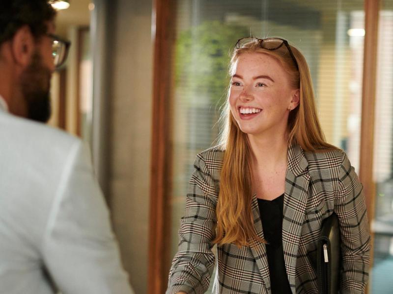 Frau schüttelt einem Mann die Hand.