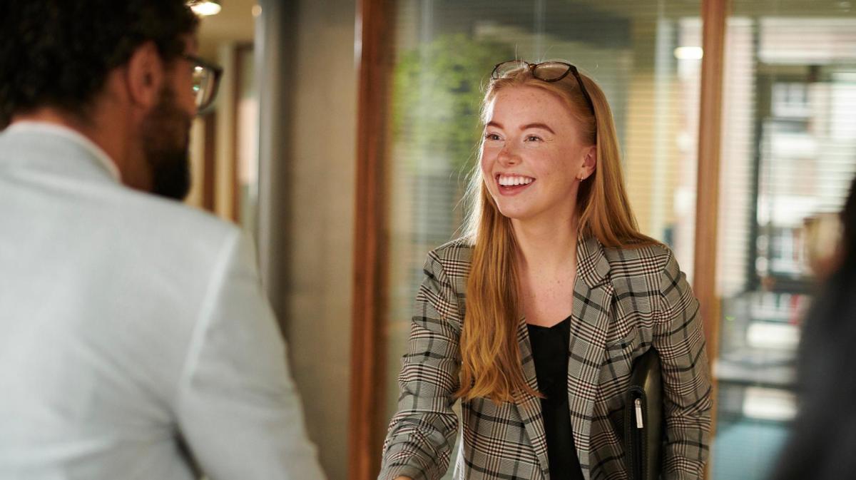 Frau schüttelt einem Mann die Hand.