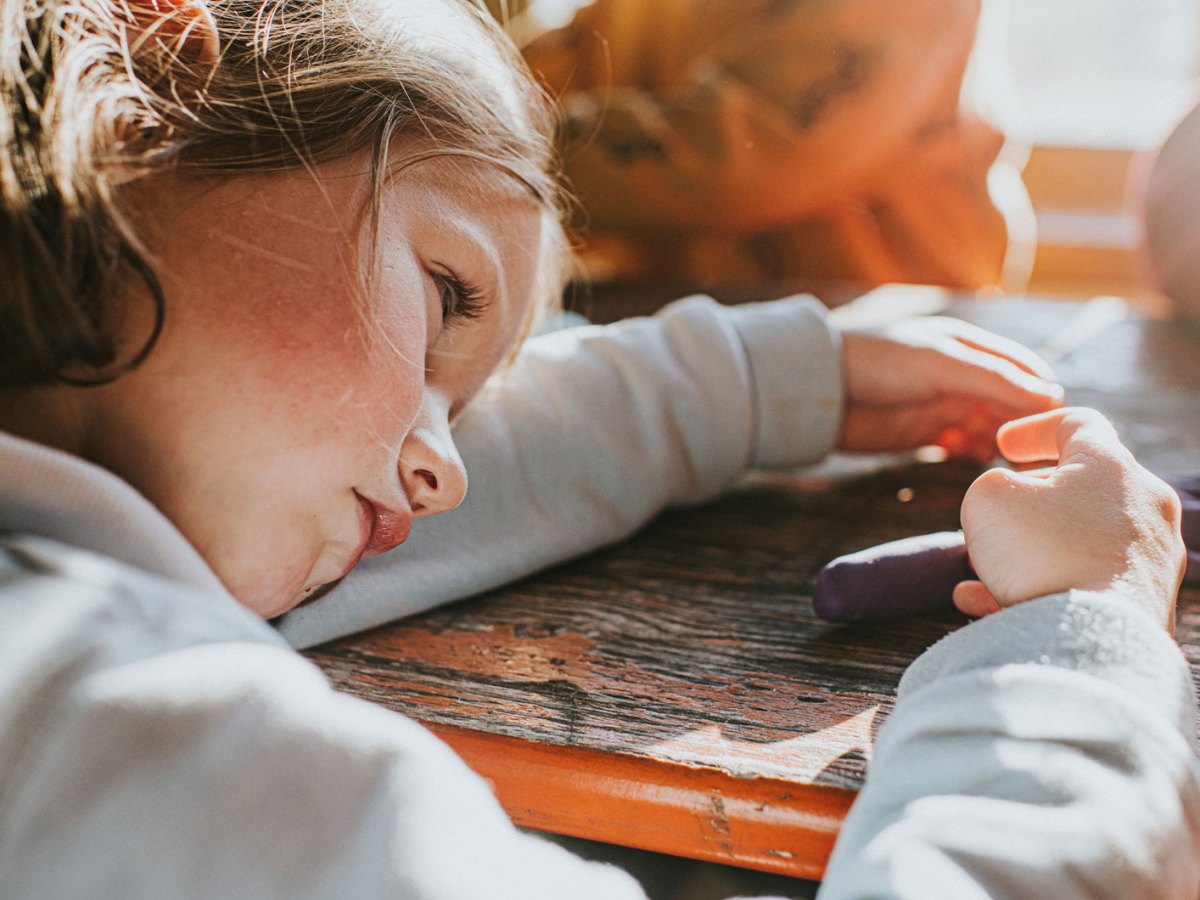 M&auml;dchen legt ihren Kopf auf ihrem Arm auf dem Schreibtisch ab, w&auml;hrend es knetet.