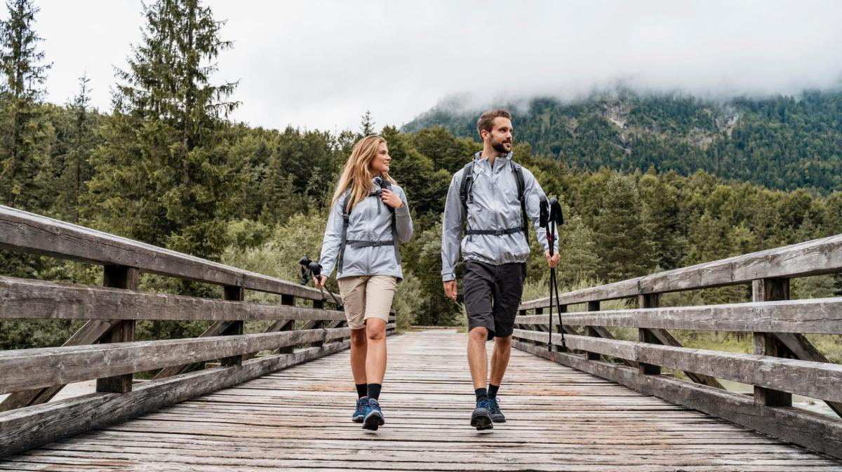 Mann und Frau gehen gerade auf einer Brücke beim Wandern.