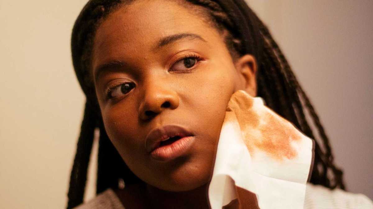 Junge Frau schminkt sich vor dem Spiegel ab.