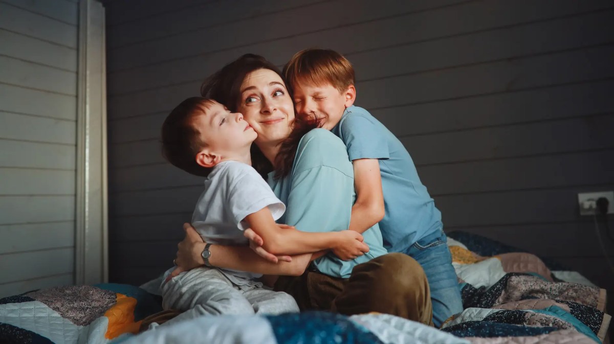 Mutter im Bett, wird von ihren beiden Söhnen am Morgen herlzlich geweckt.
