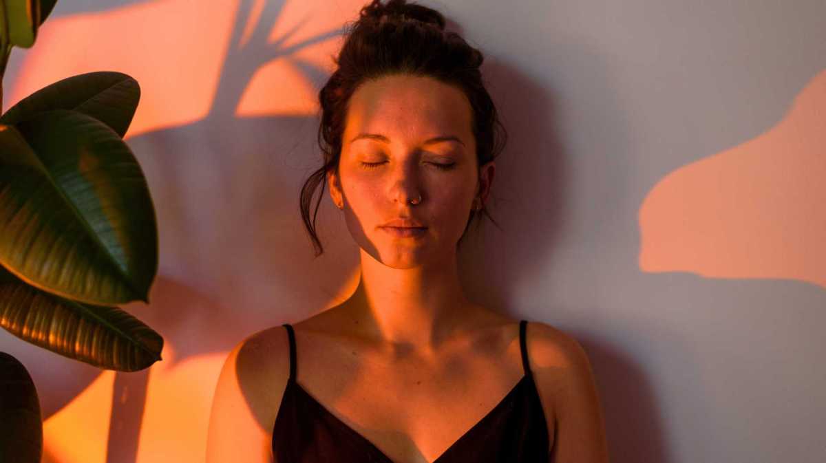 Porträt einer jungen, lockigen, denkenden Frau zu Hause mit Abendlicht.