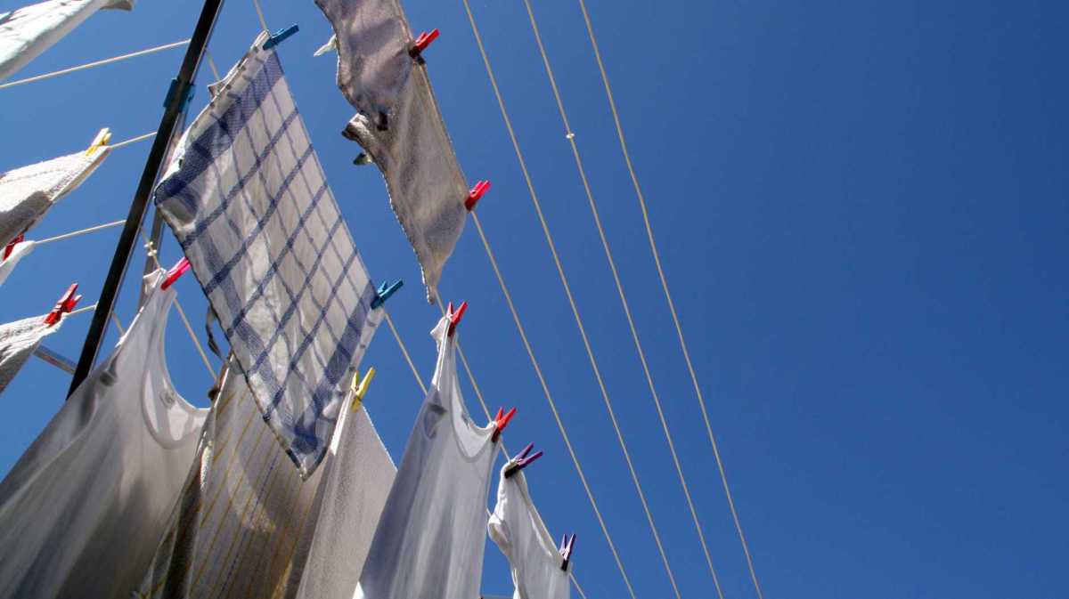 Weiße Kleidung hängt draußen in der Sonne auf einer Wäscheleine