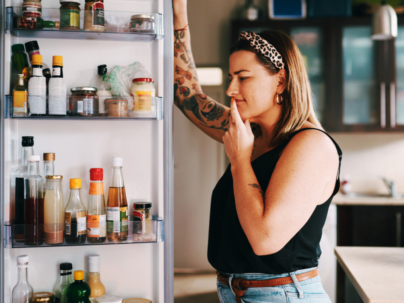 Frau steht unschlüssig vr Kühlschrank