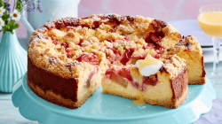 Rhabarber-K&auml;sekuchen auf einer gr&uuml;nen Tortenplatte.