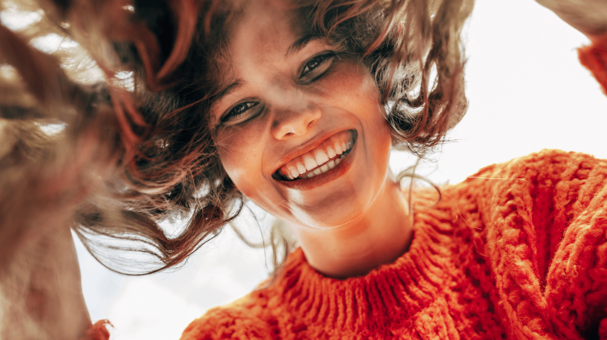 Junge Frau schaut lächelnd von oben in Kamera.